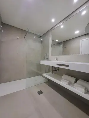 a bathroom with a shower and a sink and a mirror at Hotel Royal Orchid in Caniço