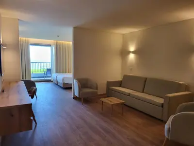 a hotel room with a couch and a bed at Hotel Royal Orchid in Caniço