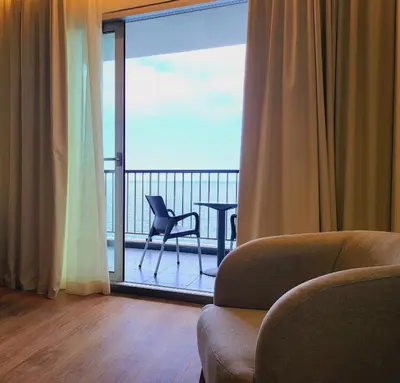 a living room with a balcony with a chair and a window at Hotel Royal Orchid in Caniço