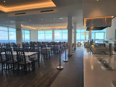 a dining room with tables and chairs and the ocean at Hotel Roca Mar in Caniço