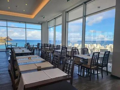 a restaurant with tables and chairs and a view of the ocean at Hotel Roca Mar in Caniço