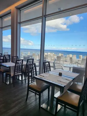 a restaurant with tables and chairs and a view of the ocean at Hotel Roca Mar in Caniço