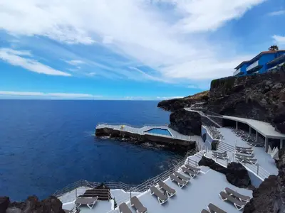 a group of chairs and the ocean on a cliff at Hotel Roca Mar in Caniço