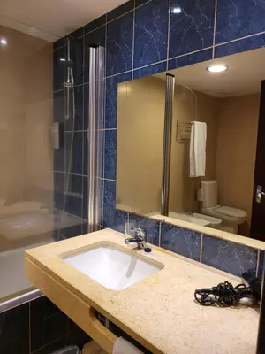 a bathroom with a sink and a shower and a mirror at Hotel Roca Mar in Caniço
