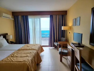 a hotel room with a bed and a desk with a television at Hotel Roca Mar in Caniço