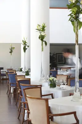 a dining room with tables and chairs with flowers in vases at Hotel Escola in Funchal