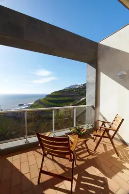 a balcony with two chairs and a table and a view of the ocean at Hotel Escola in Funchal