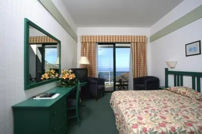 a hotel room with a bed and a desk with a mirror at Hotel Escola in Funchal