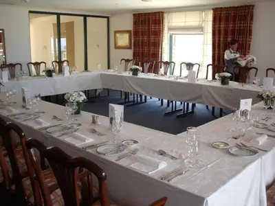 a group of tables with white table cloths and a woman in a room at Hotel Escola in Funchal