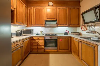a kitchen with wooden cabinets and a stove top oven at Miramar Apartment with pool by Holiday Rental Madeira in Funchal