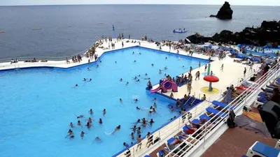 a group of people in a swimming pool near the ocean at Miramar Apartment with pool by Holiday Rental Madeira in Funchal