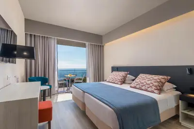 a hotel room with a bed and a view of the ocean at Enotel Magnólia in Funchal
