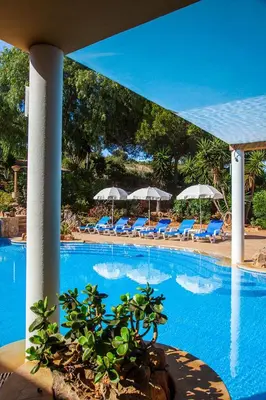 a swimming pool with chairs and umbrellas in a resort at Montinho De Ouro in Luz