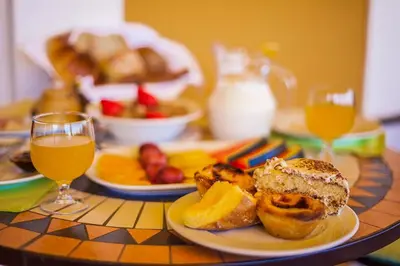 a table with a plate of food and a glass of orange juice at Montinho De Ouro in Luz