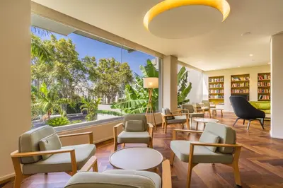 a waiting room with chairs and tables and a large window at Hotel Girassol - Suite Hotel in Funchal