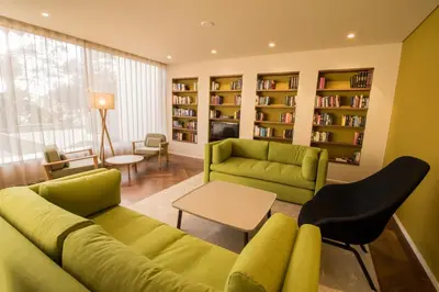 a living room with a green couch and bookshelves at Hotel Girassol - Suite Hotel in Funchal