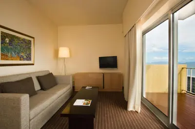 a living room with a couch and a large window at Hotel Girassol - Suite Hotel in Funchal