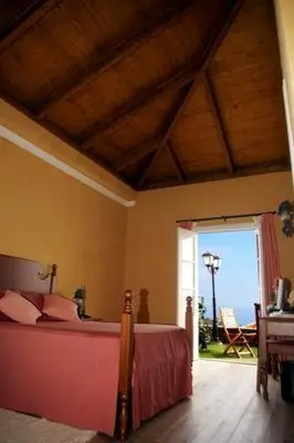 a bedroom with a bed and a door to a patio at Colina Da Faja in Fajã da Ovelha