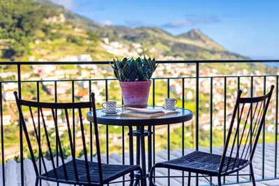 a table with two chairs and a vase on a balcony at Casa Miguel in Machico
