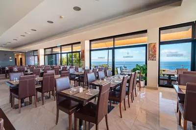 a restaurant with tables and chairs and large windows at Muthu Raga Madeira Hotel in Funchal