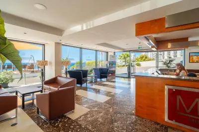 a lobby with a bar with chairs and tables at Muthu Raga Madeira Hotel in Funchal