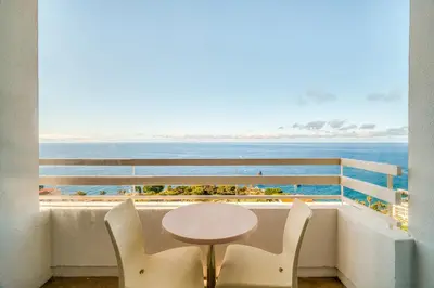 a table and chairs on a balcony with a view of the ocean at Muthu Raga Madeira Hotel in Funchal