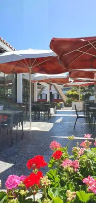 a patio with tables and chairs and flowers and umbrellas at Hotel O Colmo in Santana