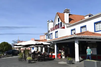 a man walking past a building with tables and umbrellas at Hotel O Colmo in Santana