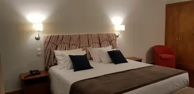 a bedroom with a large bed with a red chair at Hotel O Colmo in Santana