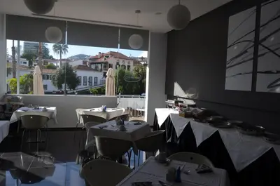 a restaurant with tables and chairs and a large window at Madeira Bright Star by Petit Hotels in Funchal