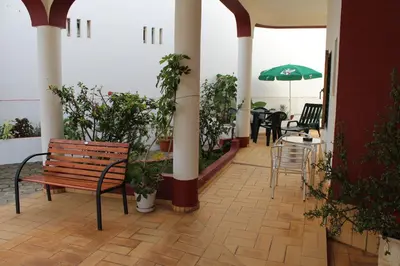 a patio with a bench and a table with an umbrella at Apartamentos e Quartos Atalaia in Sagres