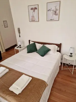a bedroom with a white bed with two pictures on the wall at Hospedaria Pôr do Sol in Funchal