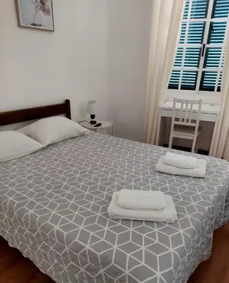 a bedroom with a white bed with green pillows at Hospedaria Pôr do Sol in Funchal