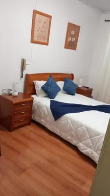 a bedroom with a white bed with green sheets and a window at Hospedaria Pôr do Sol in Funchal