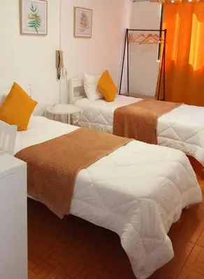a room with two beds with pink curtains and a desk at Hospedaria Pôr do Sol in Funchal