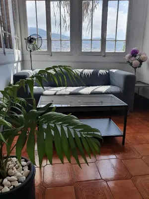 a living room with a couch and some windows at Hospedaria Pôr do Sol in Funchal
