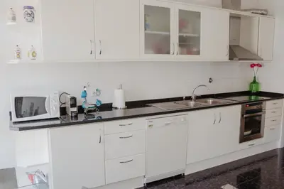 a white kitchen with a sink and a microwave at Colina Mar in Funchal