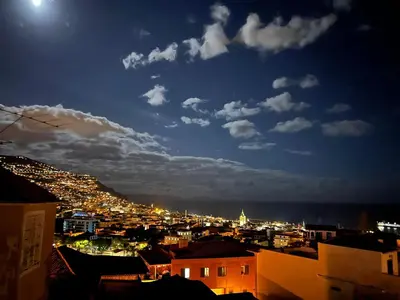 a view of a city at night with the moon at Colina Mar in Funchal