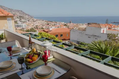 a table with a bowl of fruit on a balcony at Colina Mar in Funchal