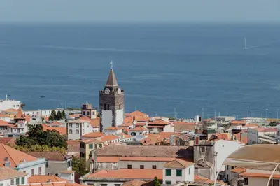 a city with a clock tower and buildings and the ocean at Colina Mar in Funchal