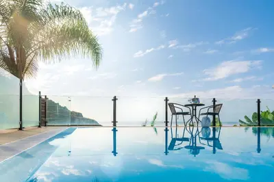a pool with a table with wine glasses on it at Zeza´s house in Calheta