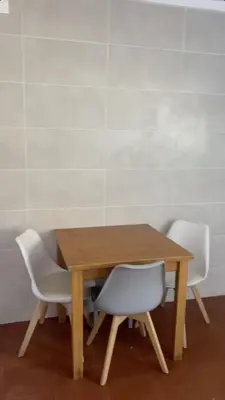 a wooden table with two white chairs around it at Cecília's House in Jardim do Mar