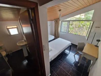 a small room with a small bed and a window at Cecília's House in Jardim do Mar