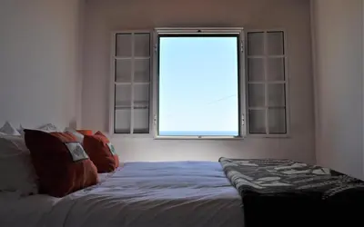a bedroom with a bed in front of a window at Cecília's House in Jardim do Mar