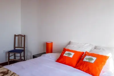 a bedroom with a bed with orange pillows and a chair at Cecília's House in Jardim do Mar