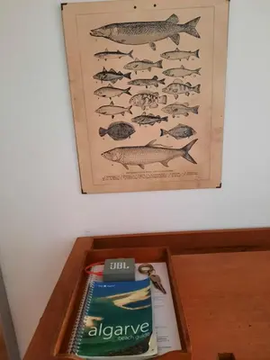 a wooden table with a poster of a group of fish at Casa Iemanjá in Vila do Bispo