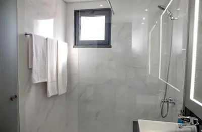 a white bathroom with a shower and a sink at Apartamento Boutique Ana Lúcia in Santa Cruz