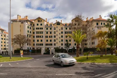 a car parked in a parking lot in front of a large building at Arcadas III by An Island Apart in Funchal