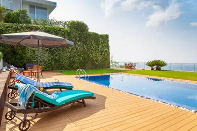 a swimming pool with two lounge chairs and an umbrella at Villa Chimera By LovelyStay in Caniço