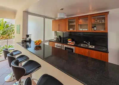 a kitchen with black counter tops and leather chairs at Apartment Blue Sea in Paul do Mar